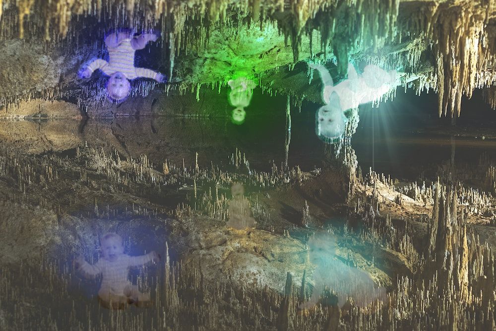 a wet cavern with glowing crystal babies growing from the ceiling, reflected in the water