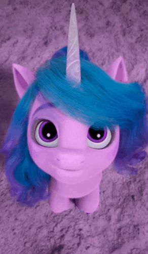 a purple unicorn with blue hair and a white horn is standing on a purple carpet .