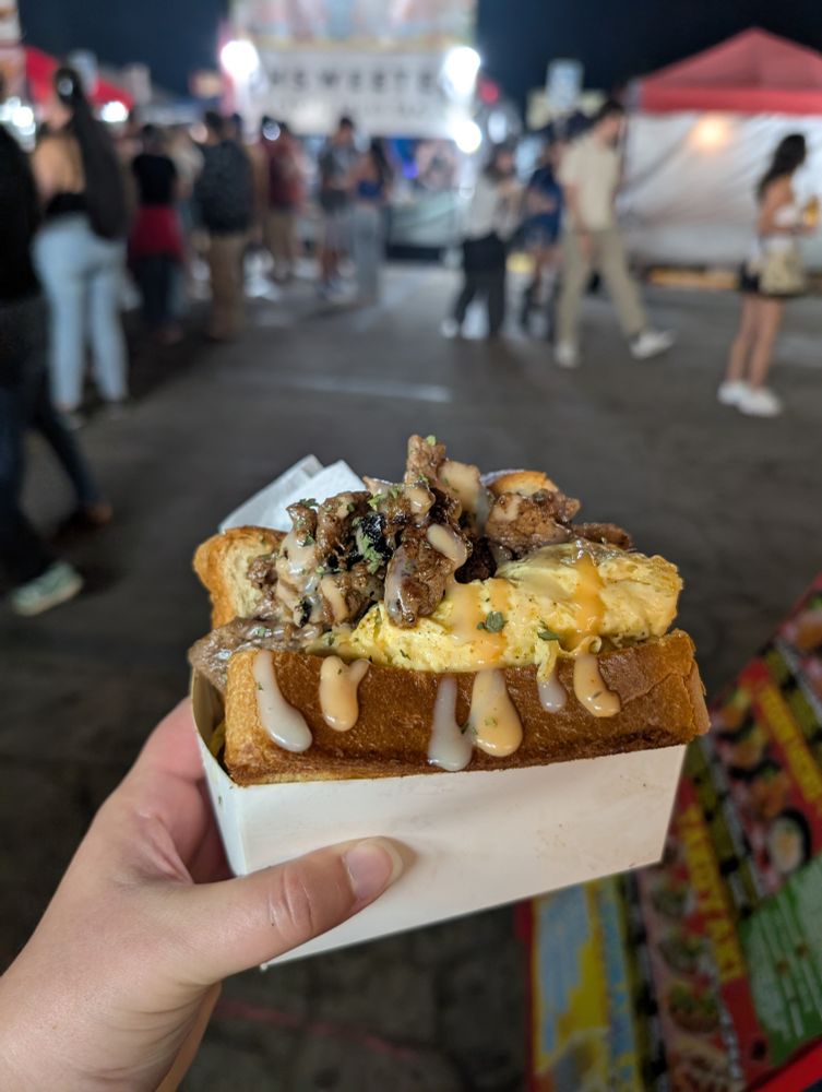A sandwich bursting with egg, beef bulgogi, and sauce between two squares of thick toast.