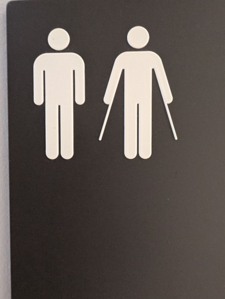 Toilet sign for gentlemen, showing two figures - one wearing a cape (or perhaps using crutches).