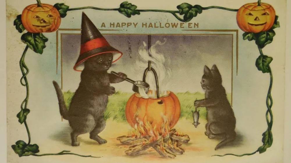Vintage postcard, two black cats around a pumpkin cauldron, one cat is holding a mouse, one is wearing a witch’s hat, decoration of a border of pumpkins.
