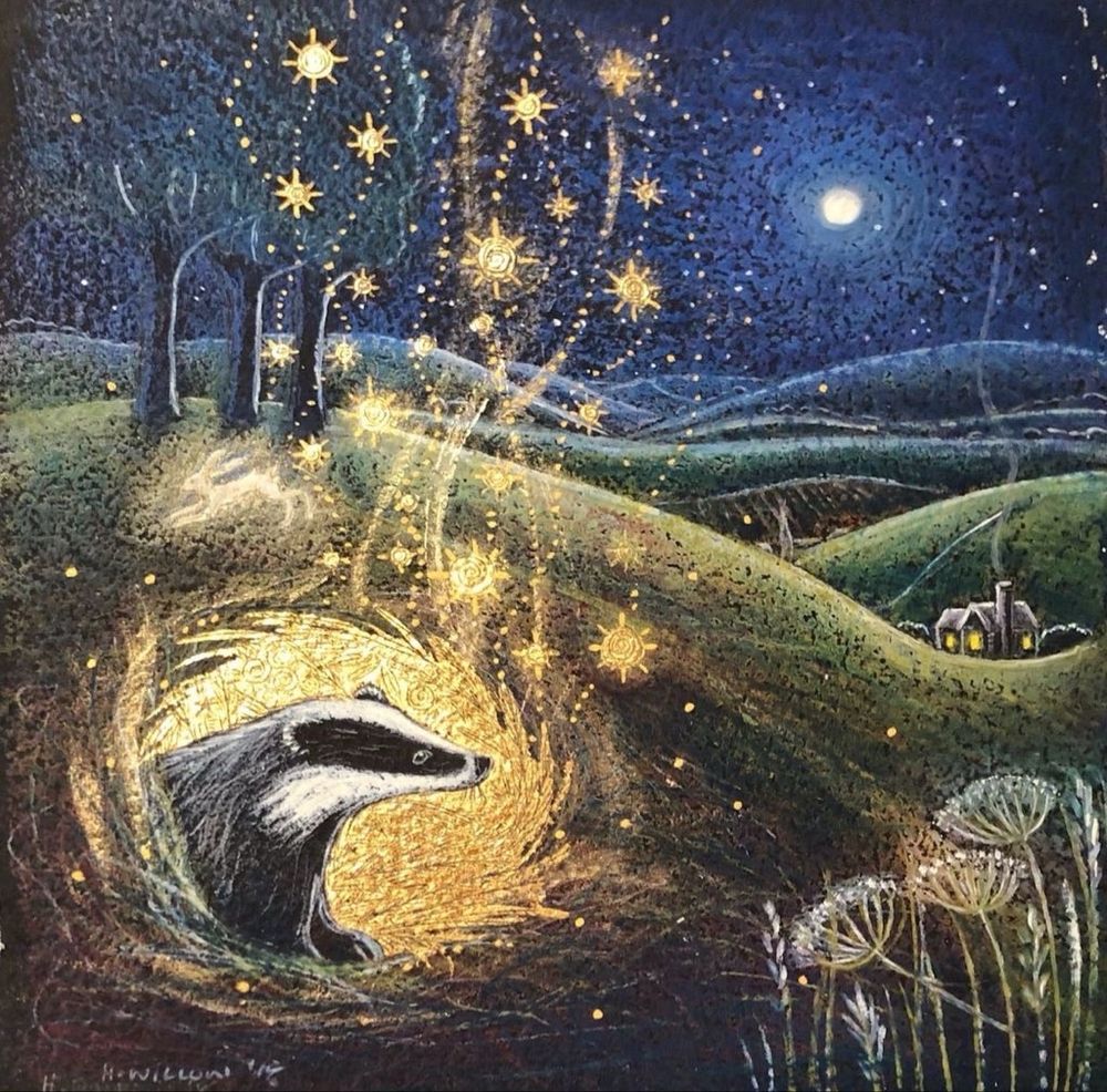 A painting titled "Beneath This Place" by artist Hannah Willow. It depicts a badger emerging from its burrow, which is glowing with golden light and stars. The scene is set at night under a full moon, with a starry sky and rolling hills in the background. A small cottage with a lit window is visible in the distance.