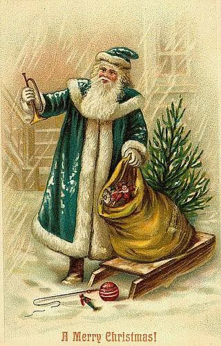 Victorian Christmas card, ‘A Merry Christmas!’ FC in green cloak with trumpet and sack with presents on a sledge and Christmas tree in snow outside a house. 