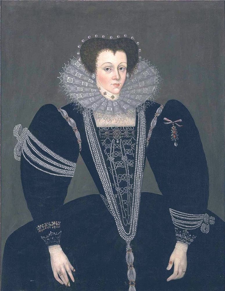 Portrait, woman wearing an Elizabethan black gown and a large, stiff, open ruff made of lace. Her dress is heavily embellished with strings of pearls draped across her bodice and sleeves. The sleeves are large and puffed. She also wears a pearl headdress.