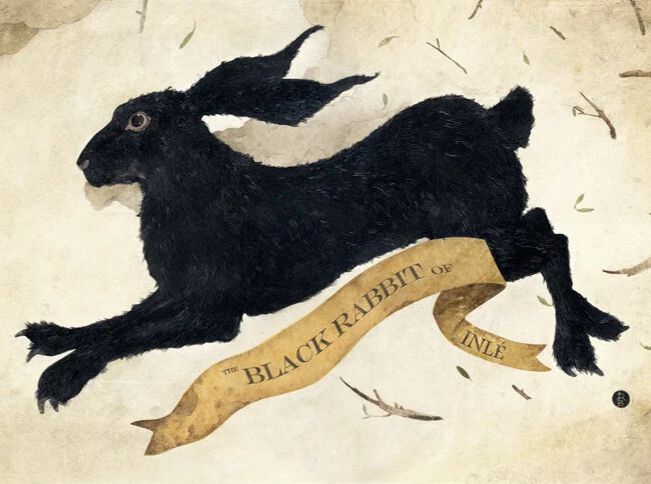 Black Rabbit of Inlé, inspired by figure from Watership Down.
The artwork features a black rabbit in mid-leap, with a tattered, pale banner wrapped around its body. The banner reads "THE BLACK RABBIT OF INLÉ." The rabbit is shown against a textured, light-colored background with scattered twig-like elements. 