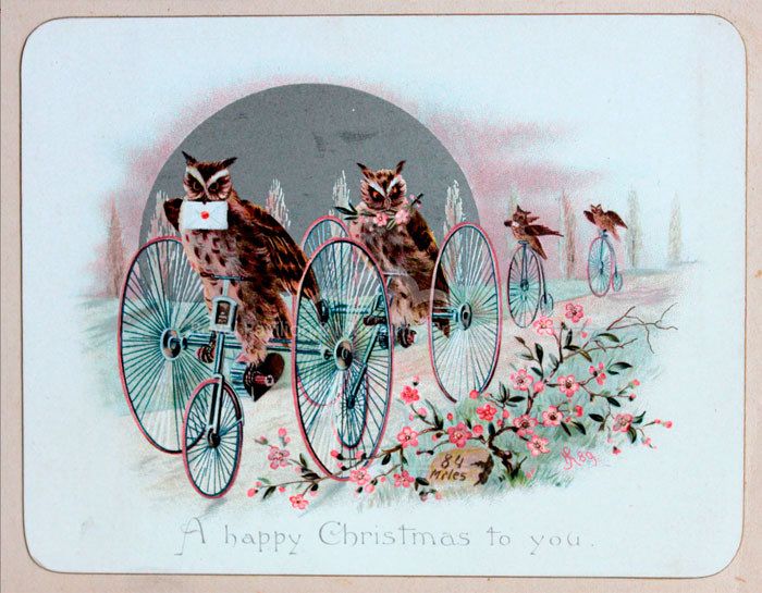 Vintage postcard, A Merry Christmas to You! Four owls are depicted riding penny farthings holding envelopes and gifts of blossom in their beaks, blossom in foreground, wintered trees in background.