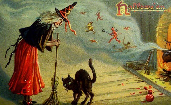 Vintage Halloween postcard with witch, broom and black cat, devils and skeletons, pumpkins in background, cauldron over fire. 