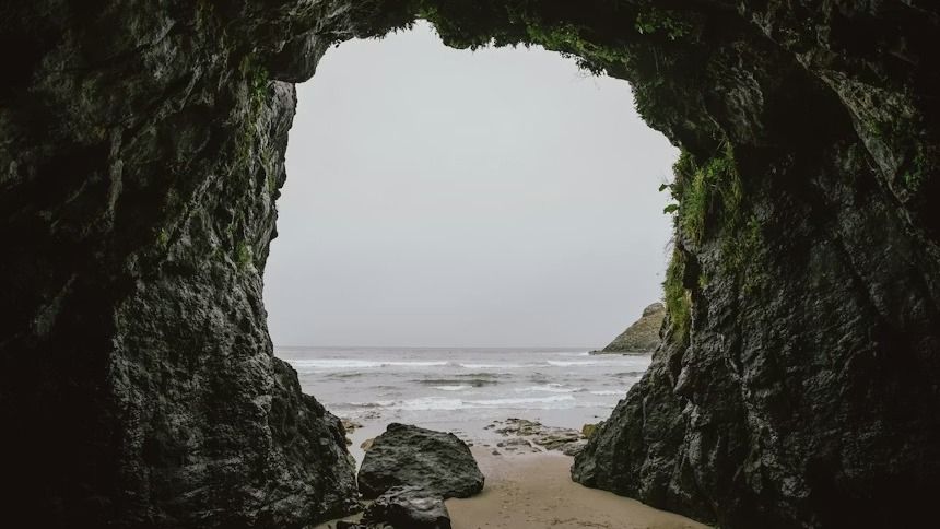 A stone cave opening with the ocean beyond.