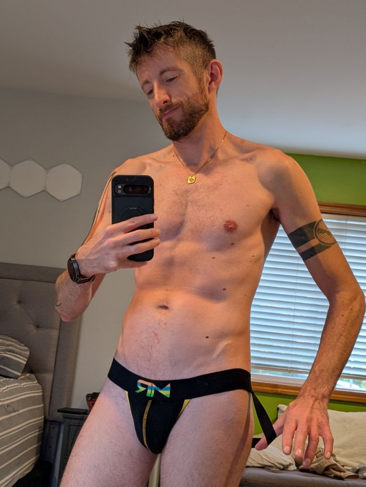 Man in a black jockstrap with color stitching accents and logo