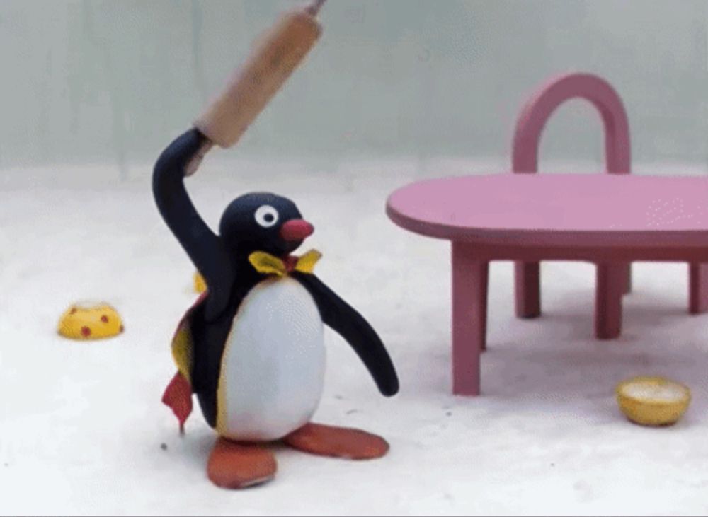 a penguin holding a rolling pin in front of a table