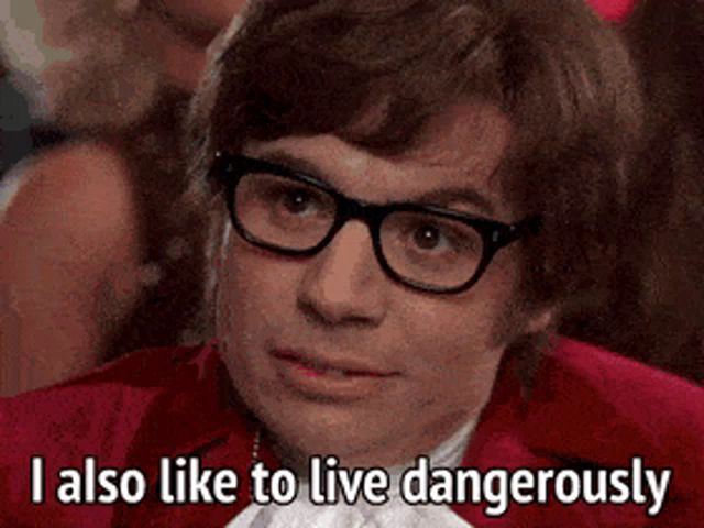 a man wearing glasses and a red jacket is saying i also like to live dangerously