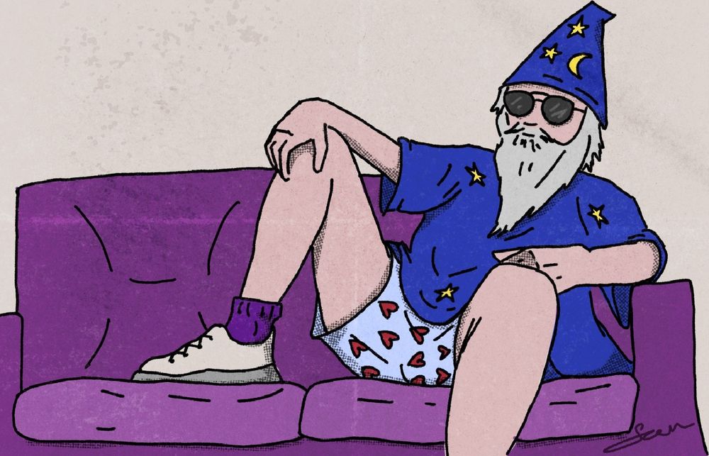 Jorge Velasquez sitting relaxed on a purple sofa. He is wearing a blue wizard robe, blue hat with stars and moon on it and boxers with hearts on the. The photo is referencing "Big Lebowski"