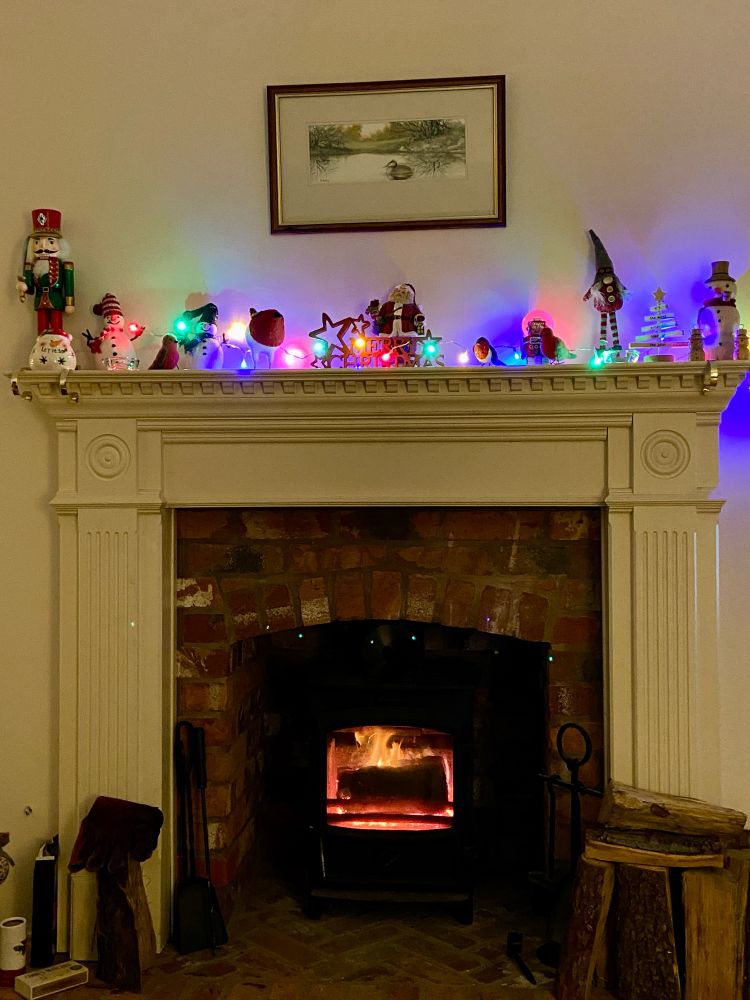 Fireplace with Christmas decorations on the mantelpiece and the log burner alight