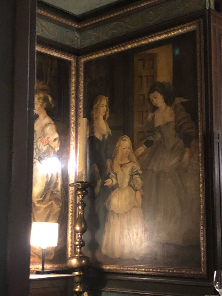 A painting in a dark restaurant of two women and a young girl. The woman on the right looks like OP (brown hair, pale) 