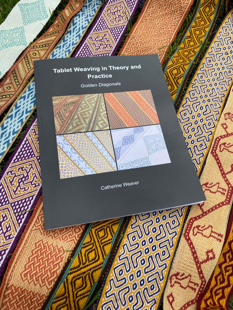 the book Tablet Weaving in Theory and Practice: Golden Diagonals lies on a bed of multicoloured tablet weaving.
