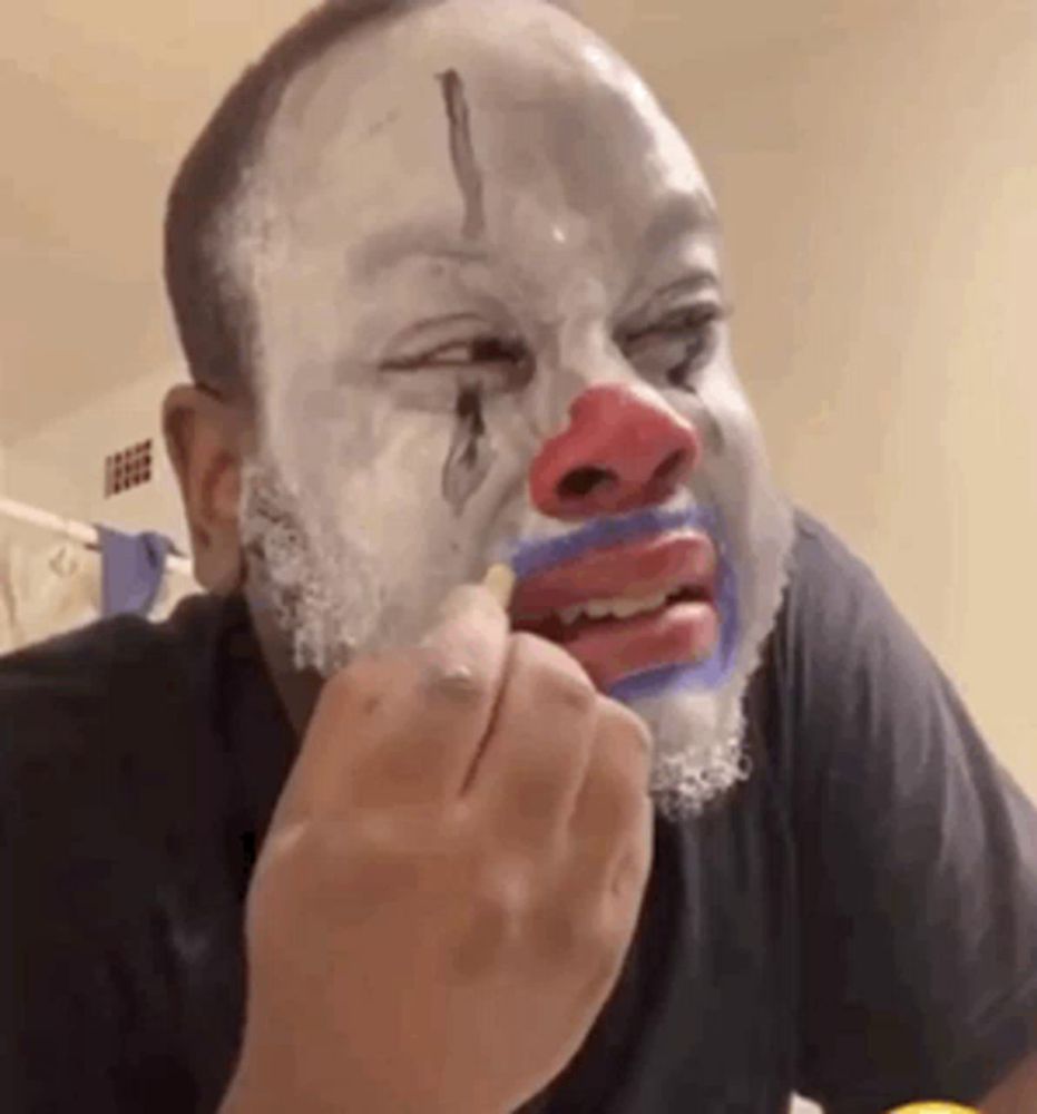 a man with a clown face painted on his face is eating a piece of food .