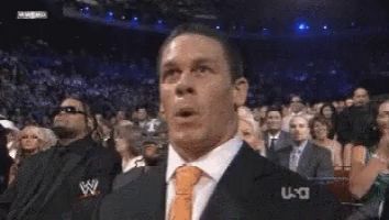 a man in a suit and tie is making a funny face while watching a wrestling match on usa