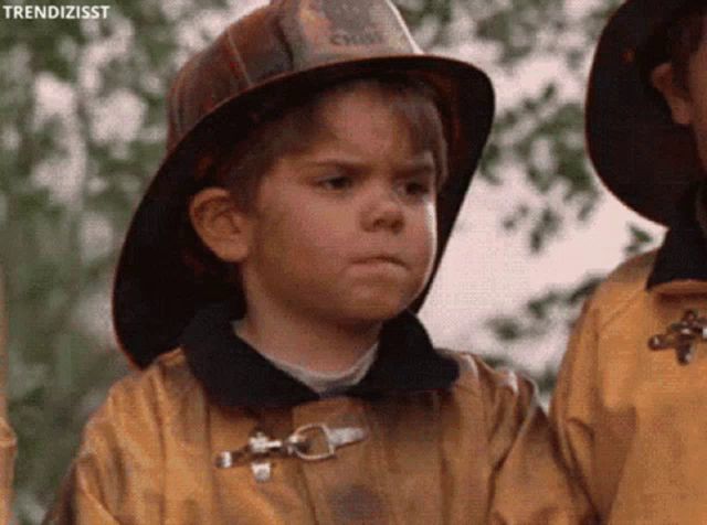 a young boy wearing a fireman 's hat and a yellow jacket