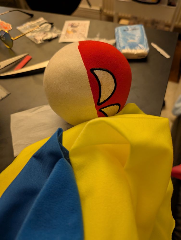 plush Polandball, with yellow and blue fabric in front of it