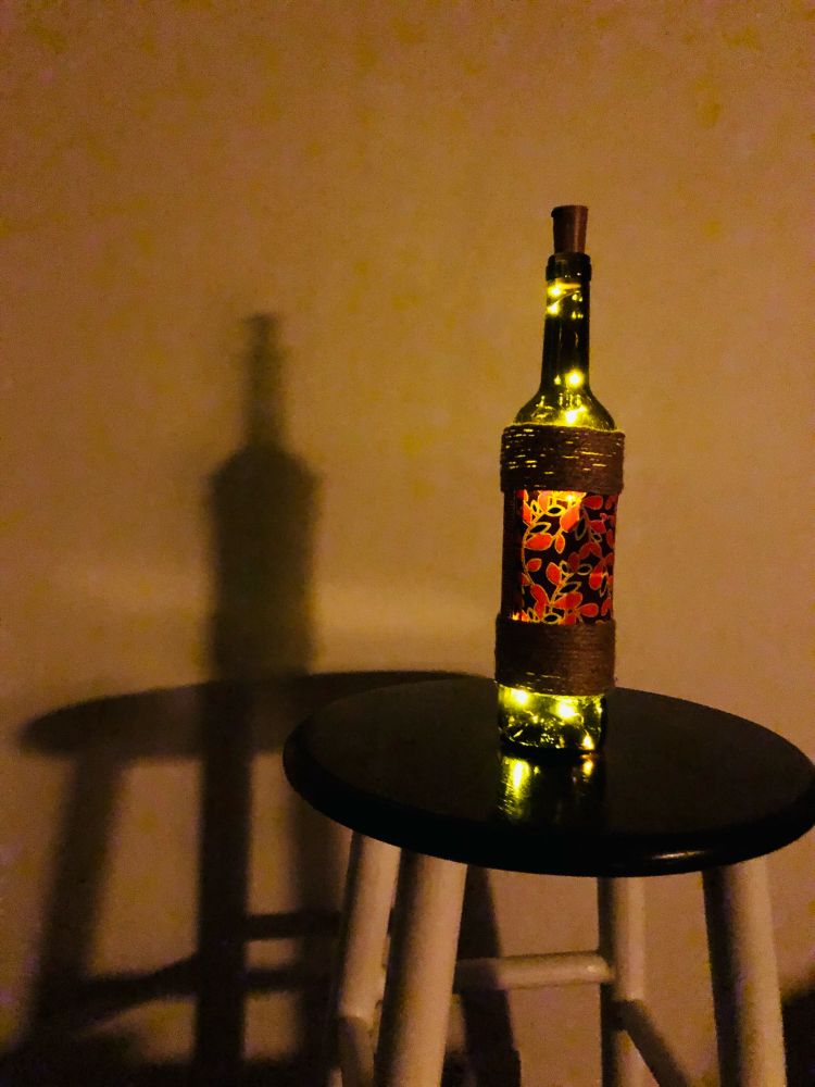 A wine bottle with decoration of African fabric and string. An LED string inside.