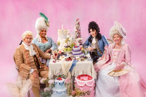Promo picture for Great British Bake Off Series 16 for Cake Week, Dame Prue and Allison are in french style Marie Anionette inspired dresses with white wigs, Prue in pink overdress and Allison in pale blue, Paul Hollywood in tan fancy coat and pants with lacy craveat and white wig, Noel in blue embroidered fancy coat with dark brown curly wig