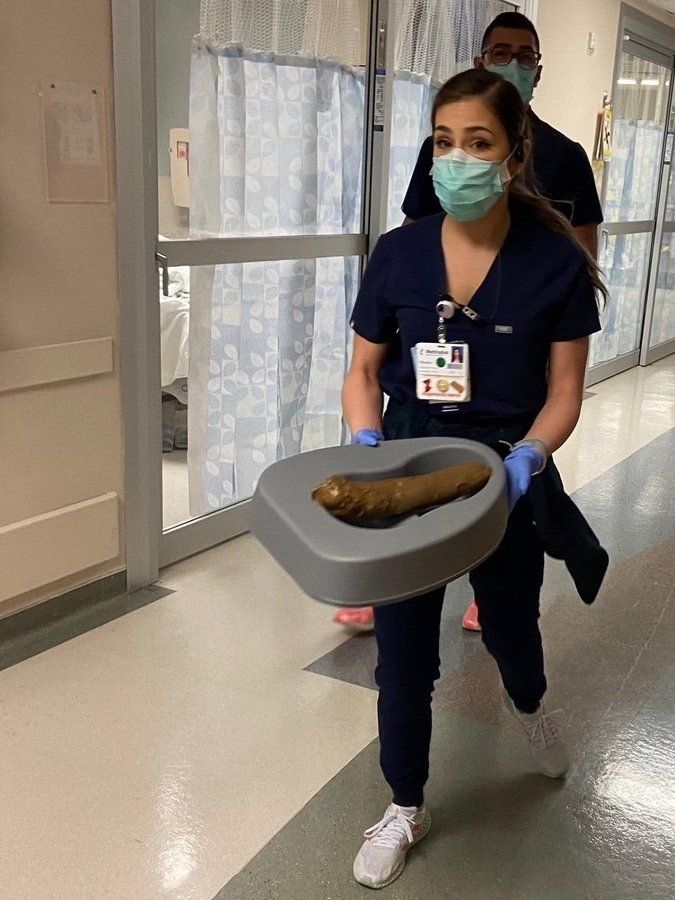 Infirmière qui transporte une cuvette contenant un très gros étron 