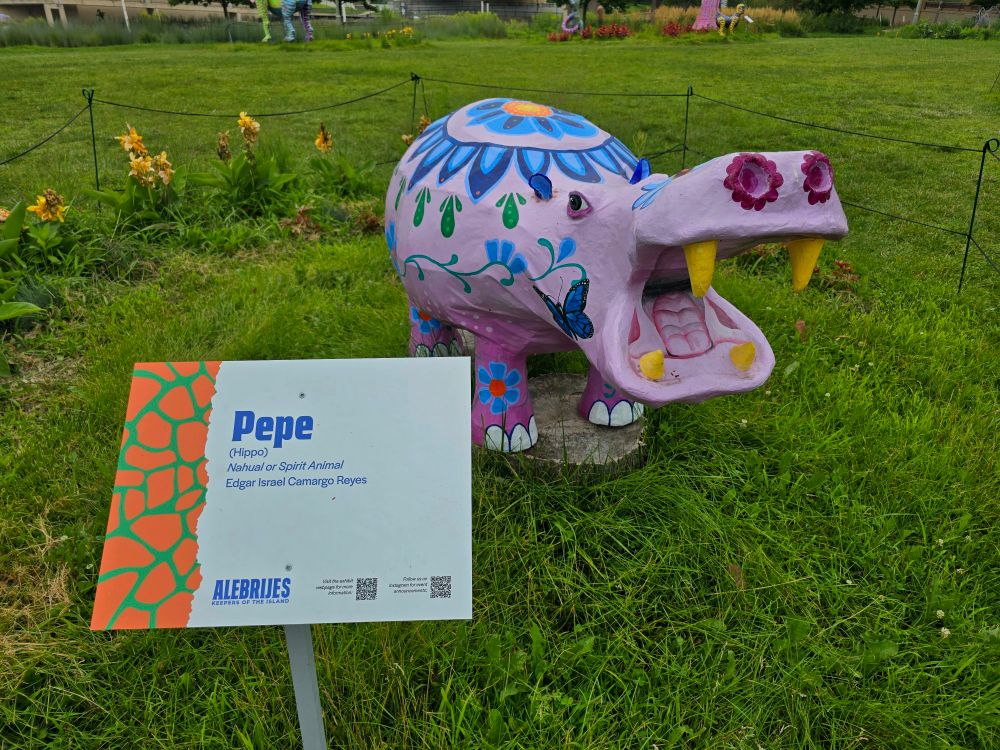 pepe: a statue of a soft pink hippo with blue flowers painted on its body.