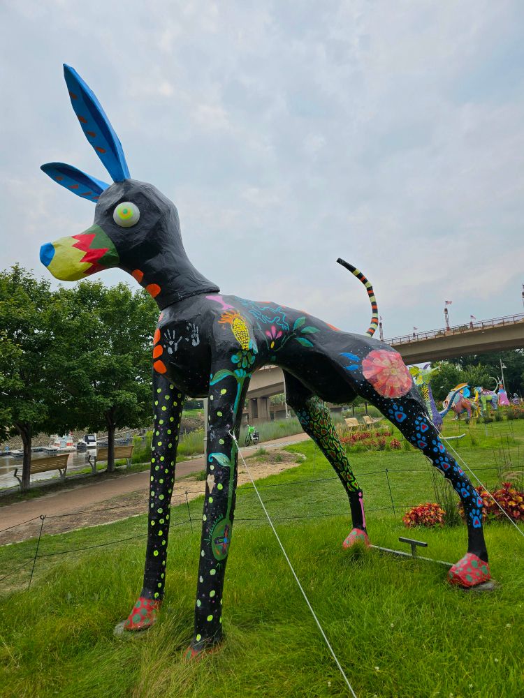 this statue was unfortunately missing its placard, but it is a giant black dog/donkey? with green dots on its legs, red feet/hooves, blue ears, and flowers and handprints on its body.