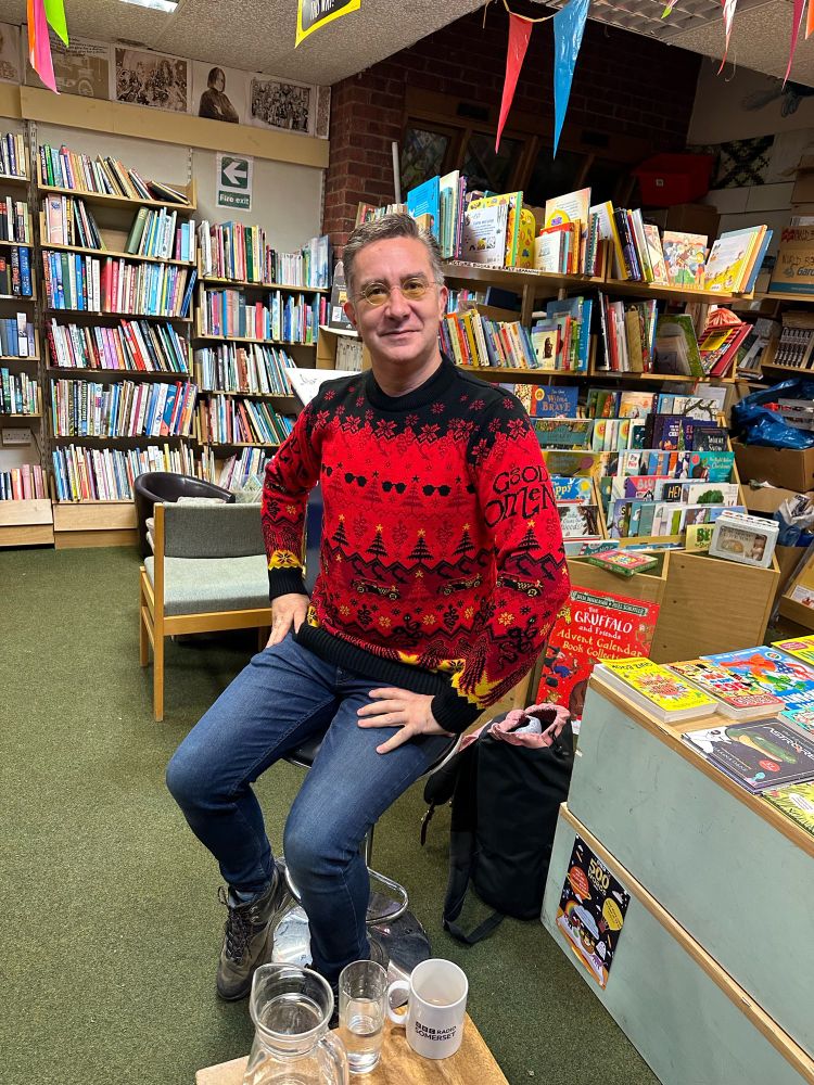 Rob looking very holly jolly in a red, black and yellow jumper with repeat patterns of dark glasses and Christmas trees