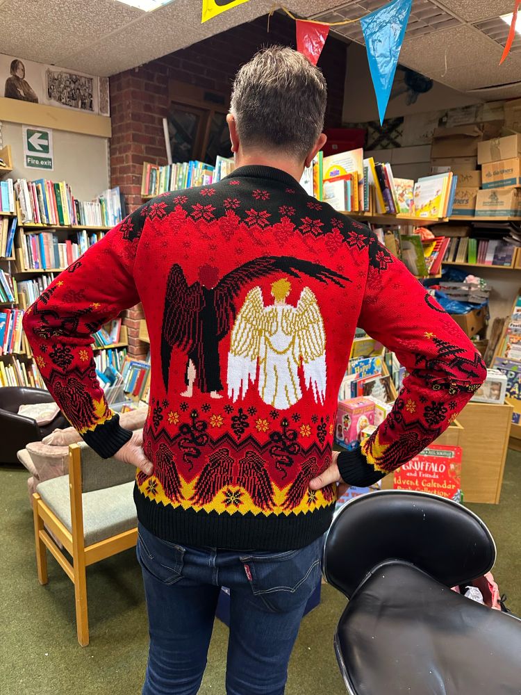 On the back of the jumper are Crowley and Aziraphale and a repeat pattern of wings