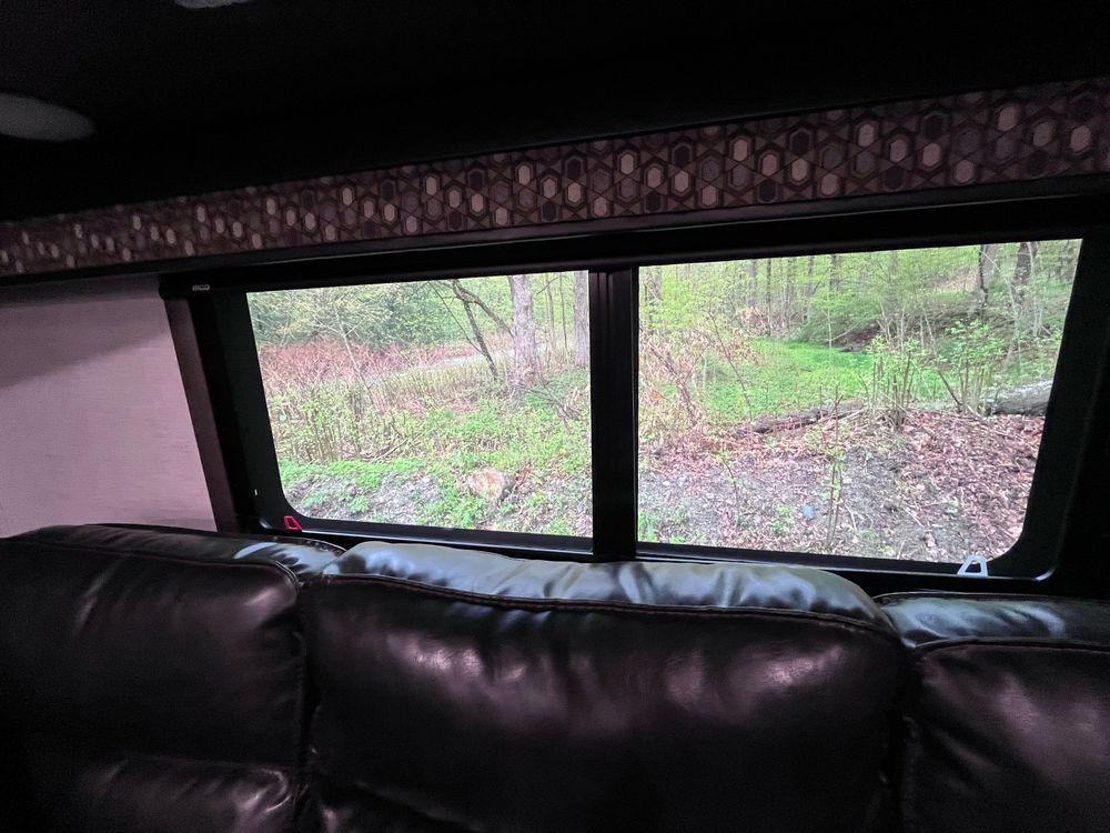 A fuzzy picture of a window above a couch and woods outside. 