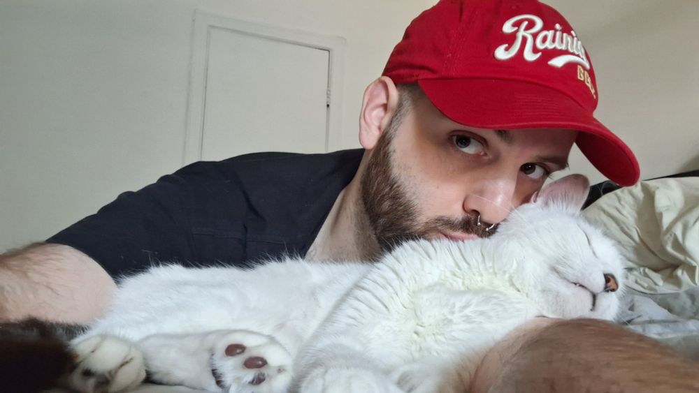 A picture of me kissing my cat while he sleeps on my arm