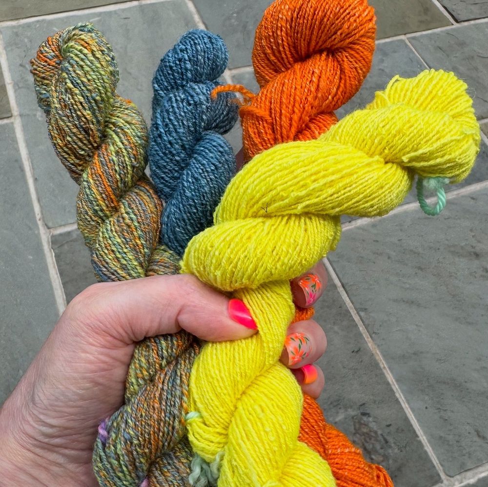 Handspun yarns in yellow, orange, blue, and a blend of all three