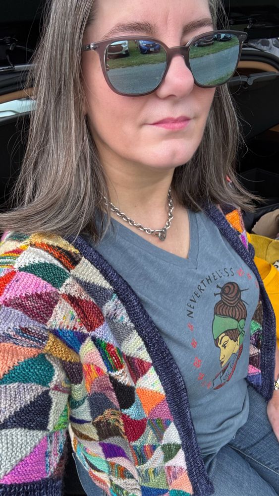 Woman wearing a hand knit open style cardigan made of colorful half square triangles