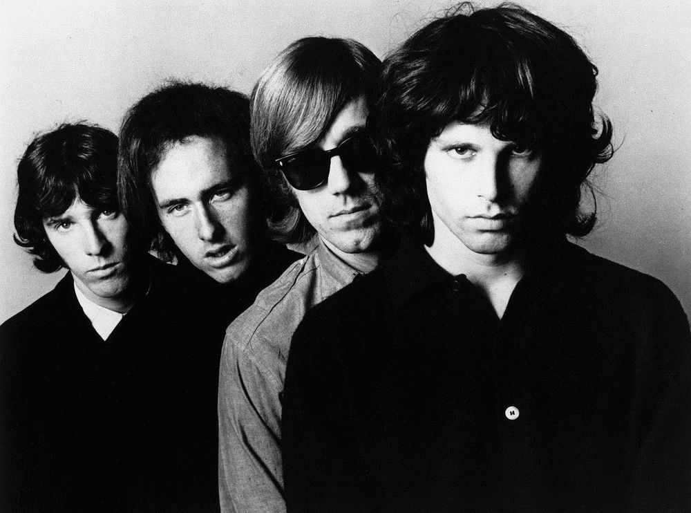 The Doors, en una fotografía promocional de Joel Brodski. De izquierda a derecha, serio, John Densmore, con la boca entreabierta, Robby Krieger, con flequillo y gafas de sol, Ray Manzarek y al frente de todos, queriendo hipnotizarnos con la mirada, parece, Jim Morrison. Elektra Records.