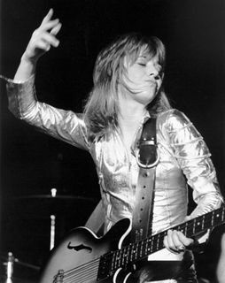 Suzi Quatro enfundada en un traje plateado ajustado, tocando un bajo eléctrico de caja hueco, mientras levanta la mano derecha en un gesto de ataque hacia las cuerdas y la izquierda reposa sobre la tercera cuerda a la altura del MI, si no me equivoco. Que para eso soy bajista. Discogs.