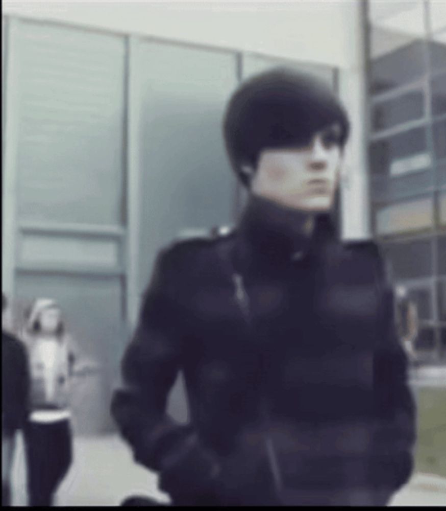 a blurry picture of a man in a black jacket standing in front of a building