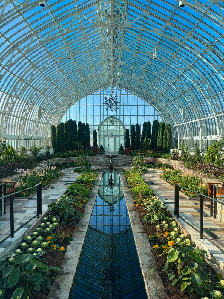 A photo of a beautiful indoor garden in a glass conservatory with high ceilings.