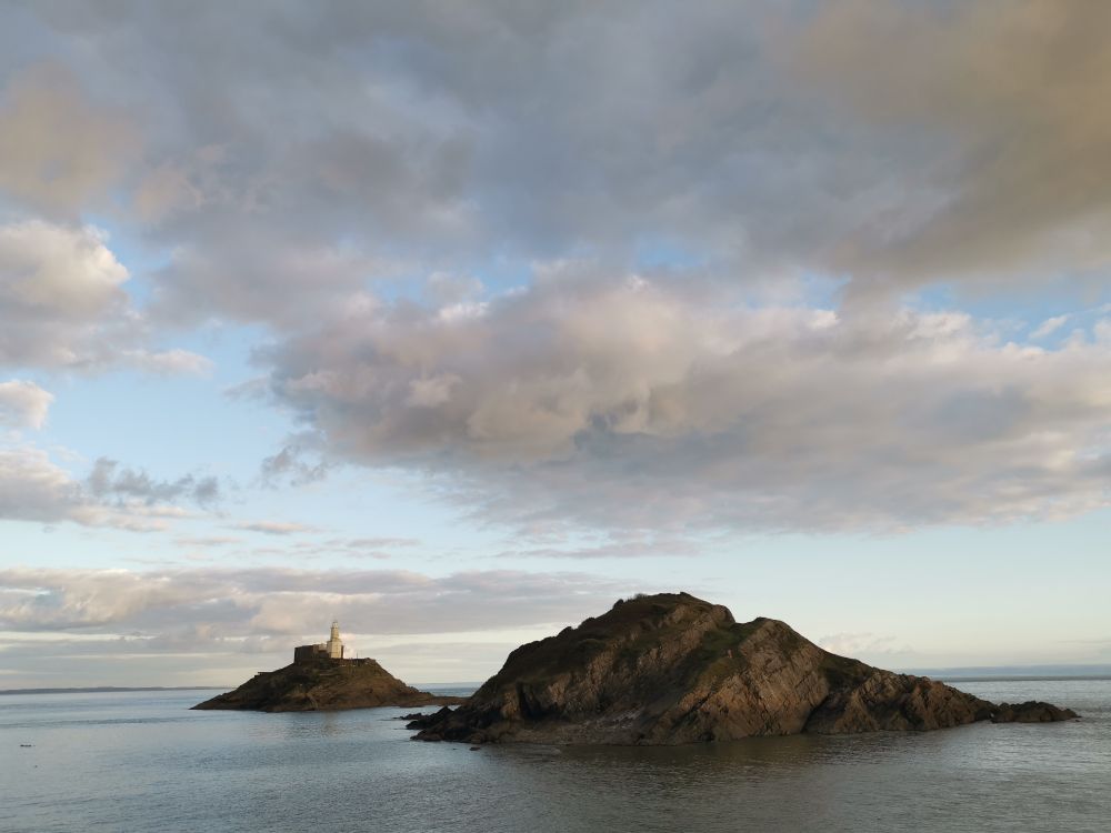 Lighthouse on rock. Sea below, sky above. 