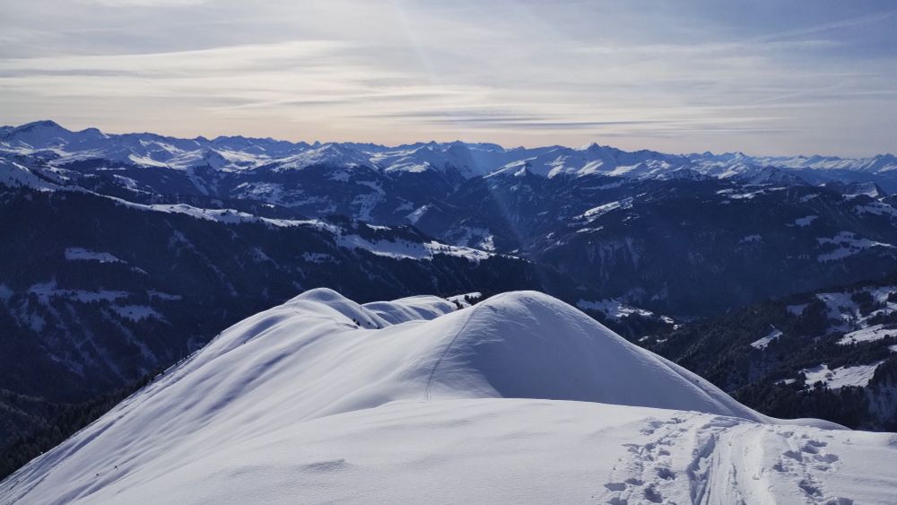 A snow covered mountain with ski climbing tracks