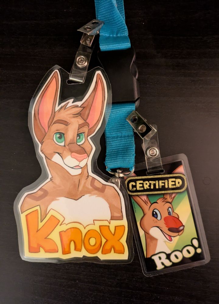 A photo of a lanyard holding two con badges: one a traditional drawing of a kangaroo bust that says Knox, the other of a generic kangaroo head that says "Certified Roo!"