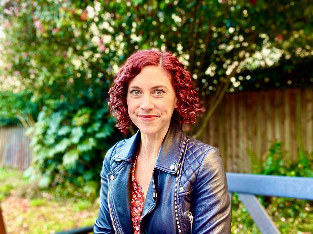 Image shows Sharon DeWitte sitting outside on a bench