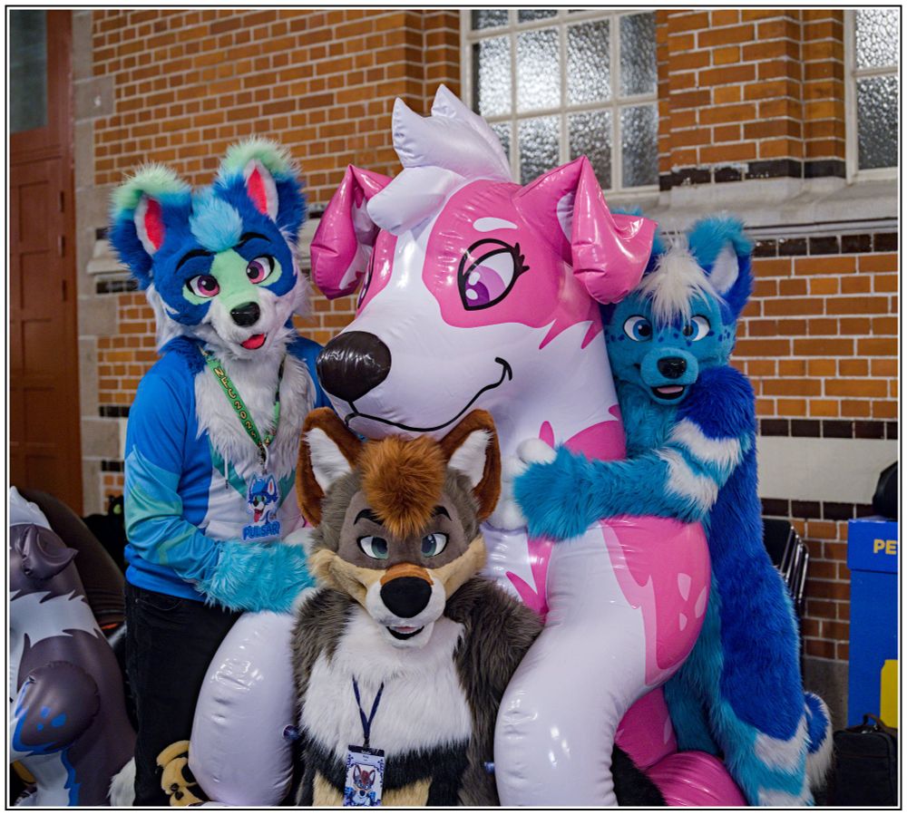 3 fursuiters cuddling around a big inflatable collie dog