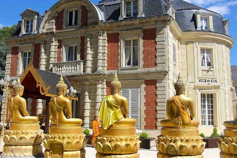 Vue rapprochée de l'ancien château de Lugny à Moissy-Cramayel. Devant, au premier plan, le dos de quatre statues de Bouddha dorées.
