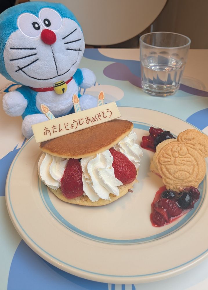 ドラえもんの誕生日をお祝いできる期間限定メニューであるどら焼きケーキとドラえもんのぬいぐるみの写真