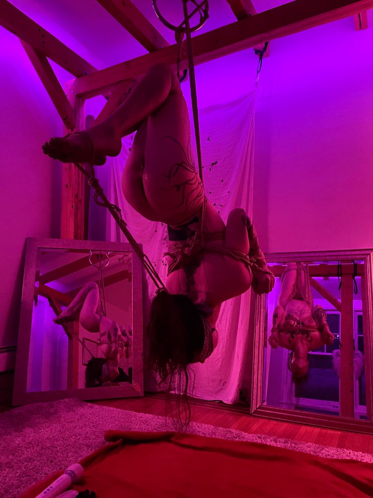 woobie suspended upside down by her waist with her arms bound in front, and her hair tied back attached to her feet and toes. she is reflected in two mirrors, one straight on, the other to her left side, but she is blindfolded, so it doesn't matter to this stupid sissy we see her from behind a little lube glistening off her used pussy. 