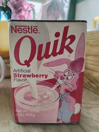 A package of strawberry quik with a cartoon bunny on the front, drinking a glass of the pink beverage.