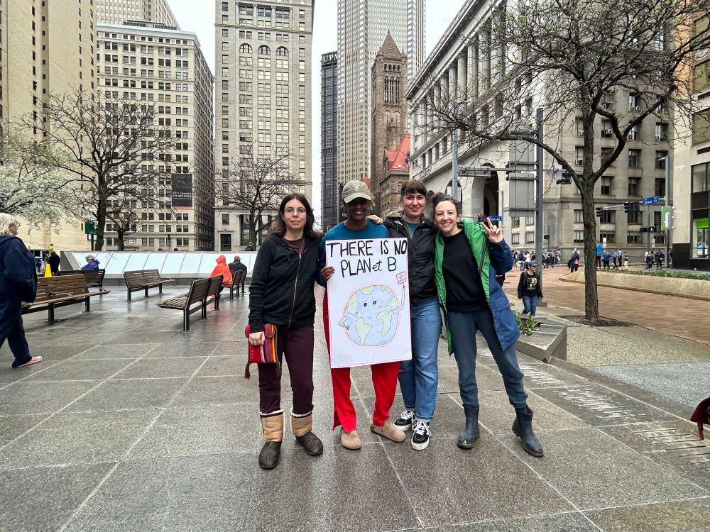 Four researchers standing in light rain at the Hands Off Pittsburgh protest