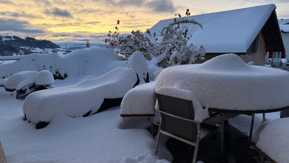 Schneebedeckte Terrasse mit Stühlen und Gartentisch