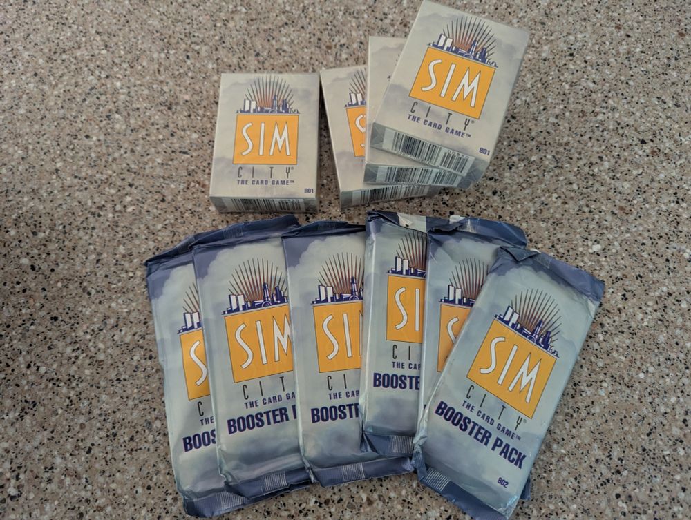 four unopened "Sim City: The Card Game" starter decks & six unopened booster packs.